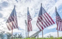 American flags flying from flag poles with a white cloud background.Finding Inspiration in Sacrifice: Celebrating Memorial Day with a Motivated Mindset